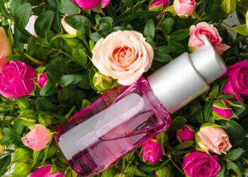 Bottle of fragrance or aromatic oil in a bunch of fresh flowers